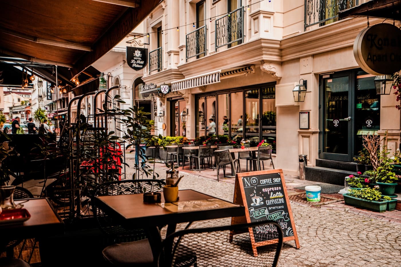 Sunlit terrace of Djermots Café with plants and bistro tables